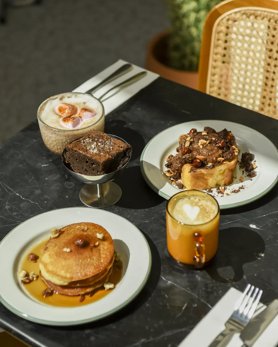 Pancakes, brownie, latte et chocolat chaud aux marshmallows sur une table en marbre