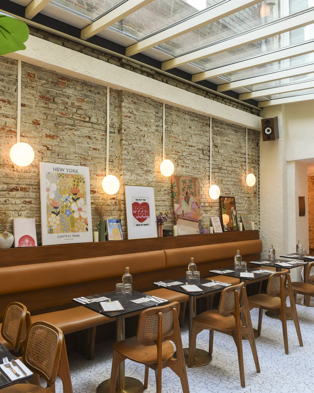 La salle du Boom Boom : banquettes en cuir camel, mur de briques, affiches et grande verrière